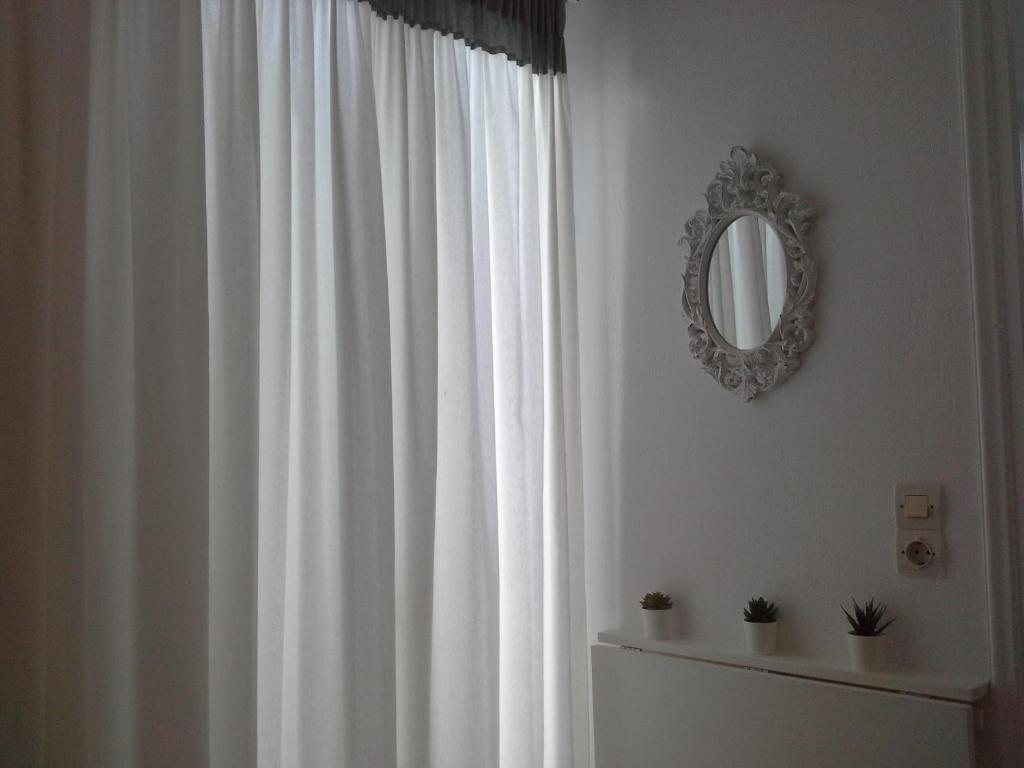a bathroom with a white curtain and a mirror at Kiklamino Sunset Studios in Oia