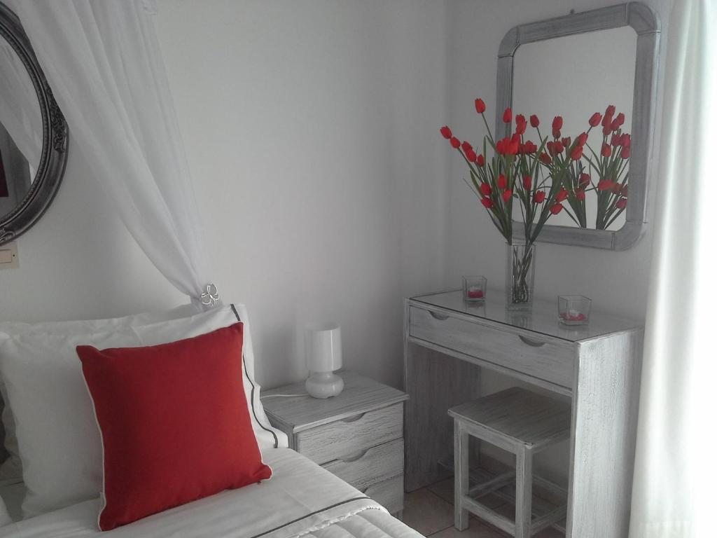 a bedroom with a red pillow and a table with a mirror at Kiklamino Sunset Studios in Oia