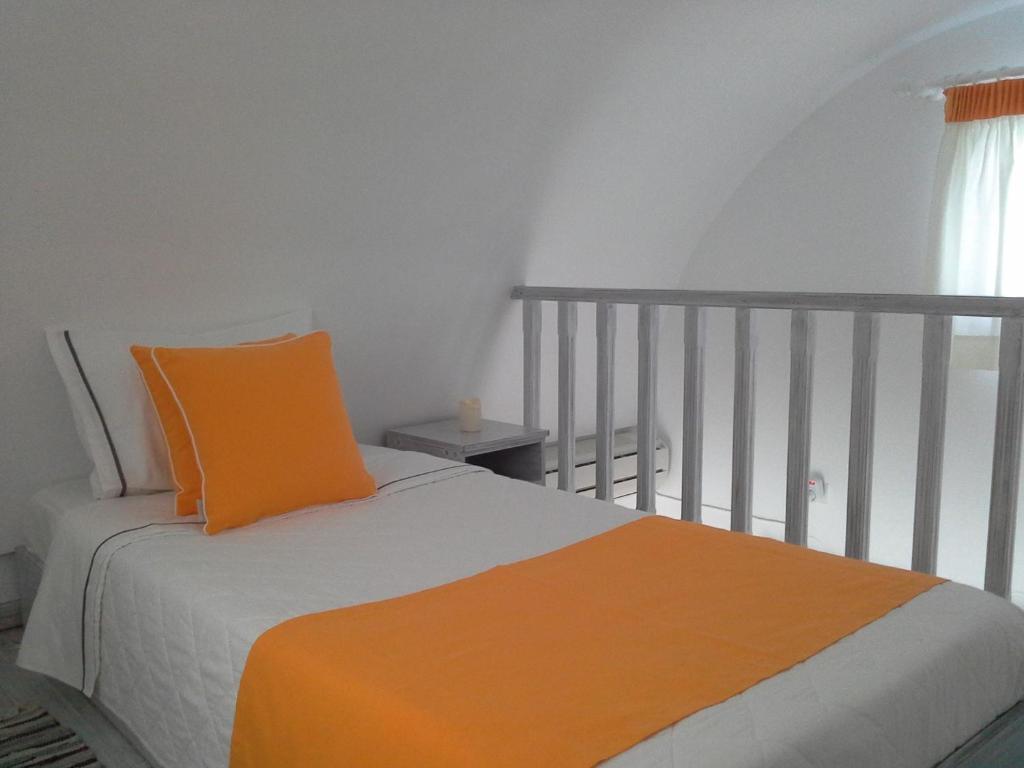 an orange pillow on a bed in a bedroom at Kiklamino Sunset Studios in Oia