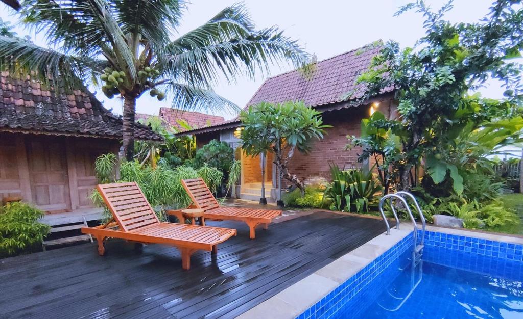 2 sillas sentadas en una terraza junto a una piscina en The Amrta Borobudur en Borobudur