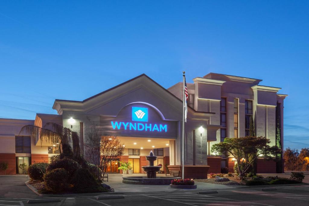 a hotel with a sign on the front of a building at Wyndham Visalia in Visalia