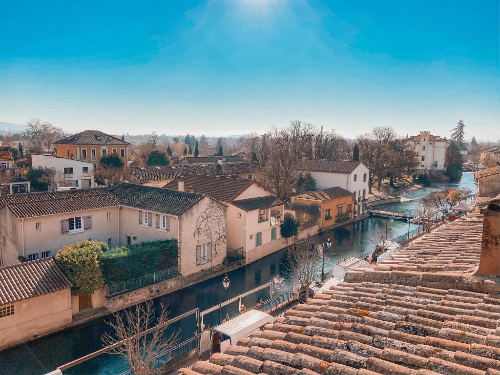une vue d'une ville avec une rivière et des bâtiments dans l'établissement LE BELVEDERE, à LʼIsle-sur-la-Sorgue
