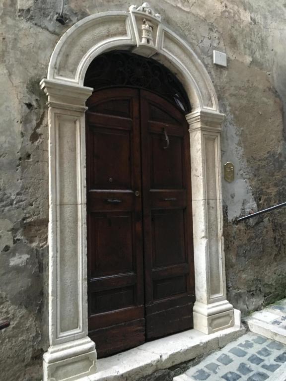 - une porte en bois dans un bâtiment en pierre avec une arche dans l'établissement Antica Dimora della Chiesa, à Olevano Romano