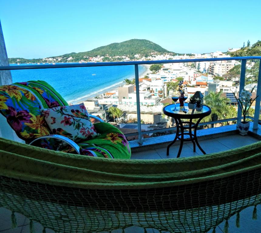 einen Balkon mit einem Tisch und Meerblick in der Unterkunft Residencial Jardim dos Beija- Flores in Bombinhas