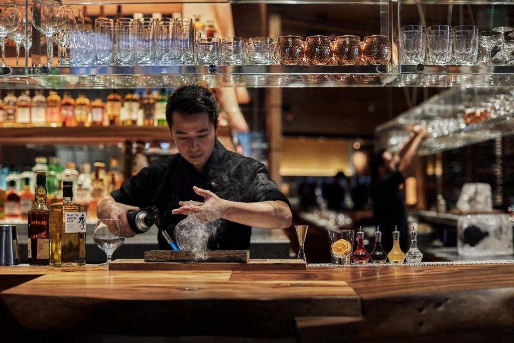 a man standing behind a bar making a drink at Four Seasons Hotel One Dalton Street, Boston in Boston