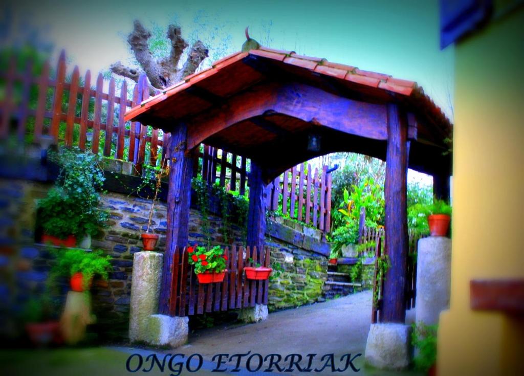 a wooden gazebo with potted plants and a fence at Perlakua Saka in Deba