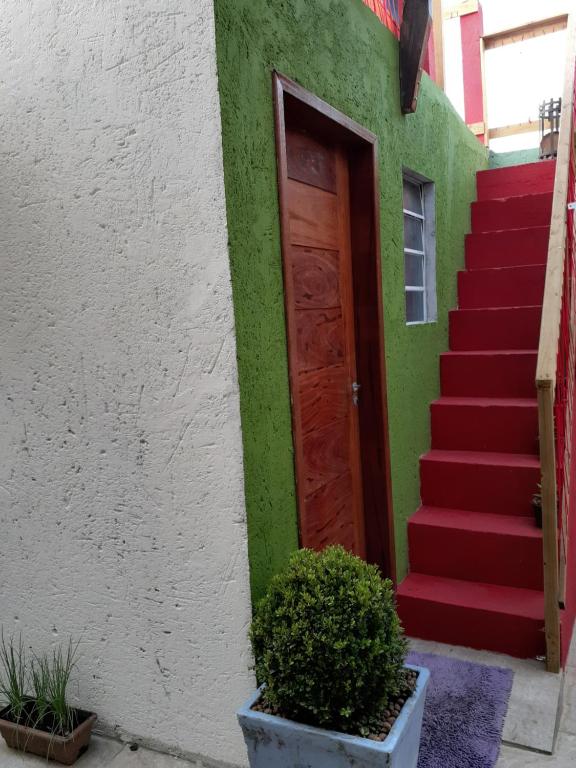una casa con una puerta roja y escaleras rojas en Suites em Floripa, en Florianópolis