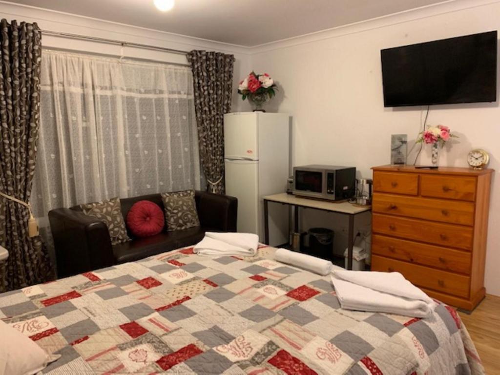 um quarto com uma cama, um sofá e um frigorífico em Ascot Comfort em Perth