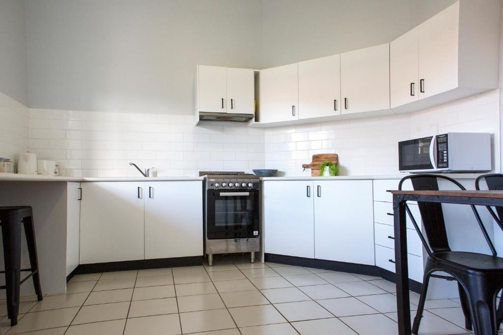 a kitchen with white cabinets and a black oven at Revive Central Apartments in Temora
