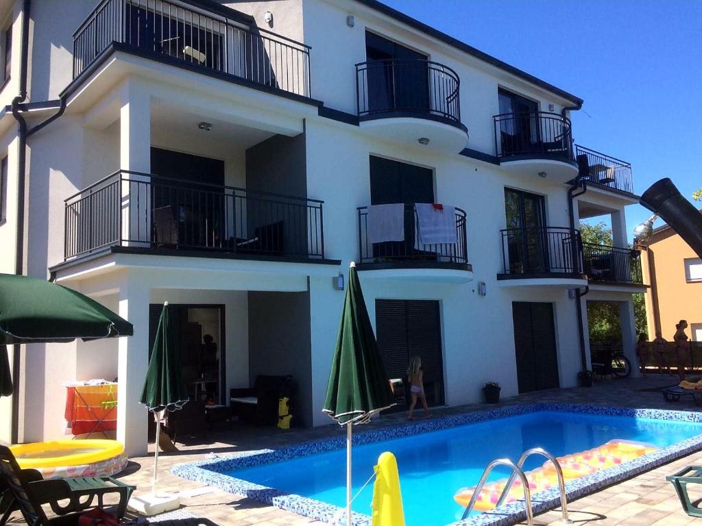 a building with a swimming pool in front of a house at Apartmani Zaric in Malinska