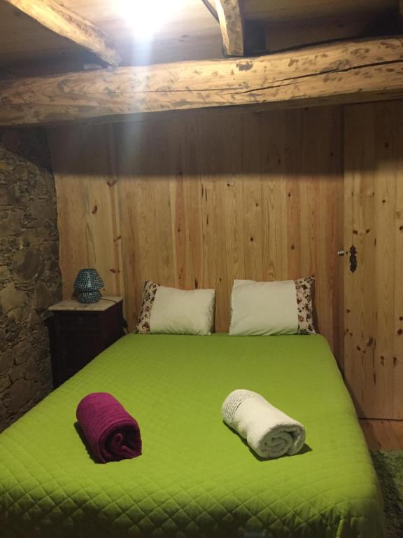 a bedroom with a green bed with two towels on it at Casa de Baixo in Lousã
