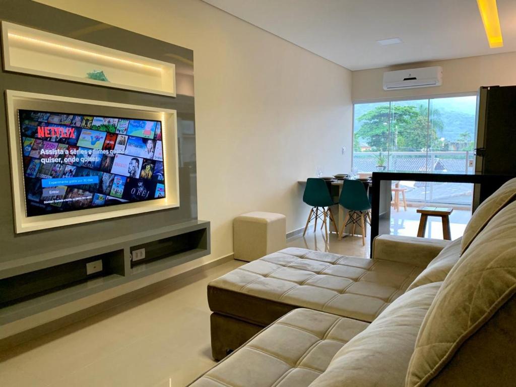 uma sala de estar com um sofá e uma televisão de ecrã plano em Apto Alto Padrão C/Ar Condicionado e Área Gourmet. em Ubatuba