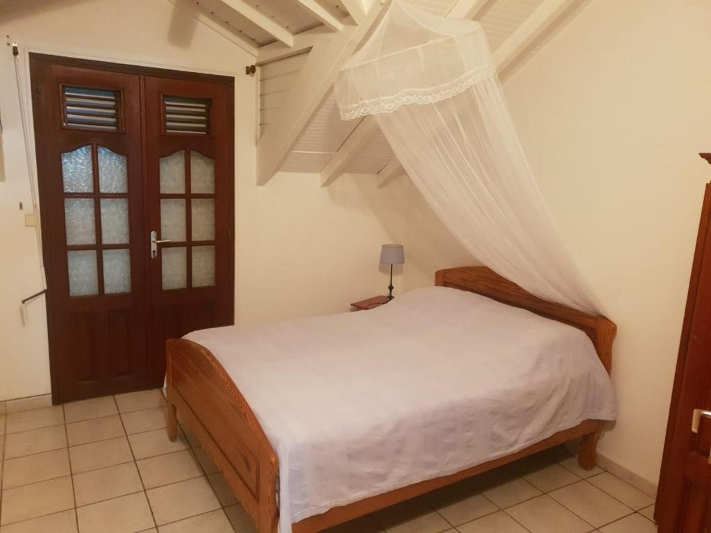 a bedroom with a bed with a mosquito net at LE ZAGOUTI in Capesterre