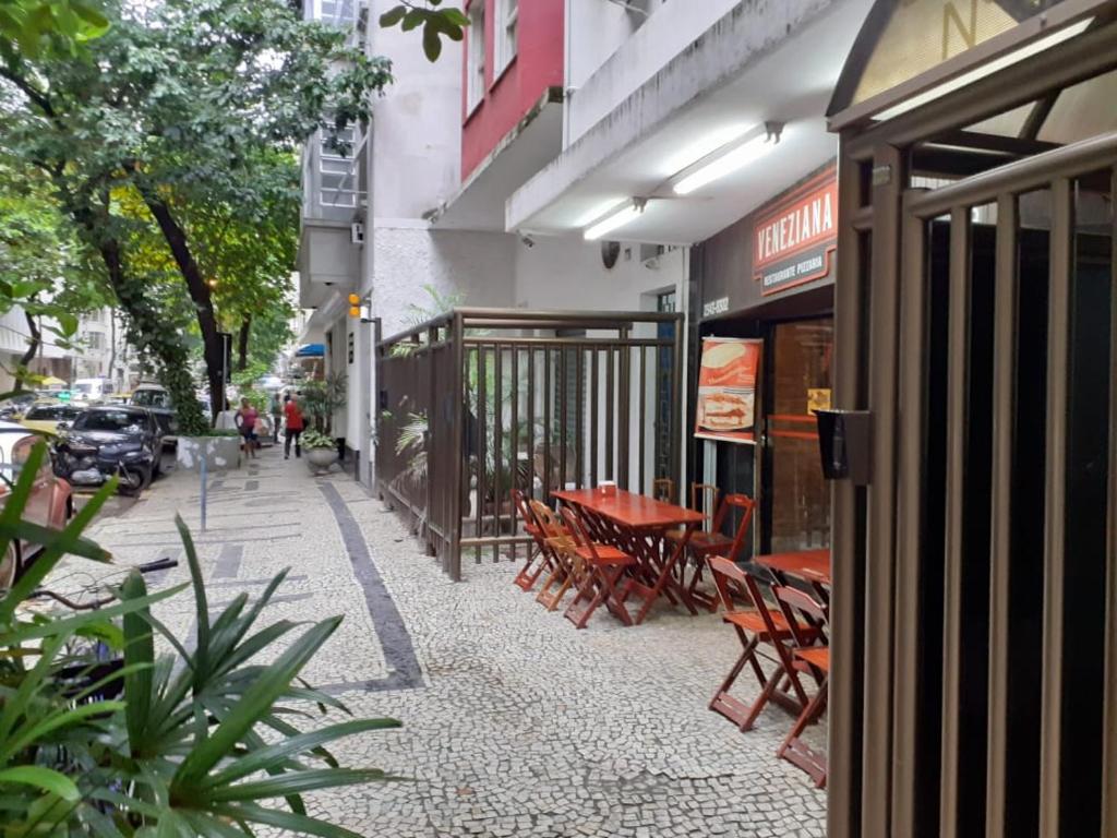 um passeio com mesas e cadeiras em frente a um edifício em Copacabana / Lema, a uma quadra da praia no Rio de Janeiro