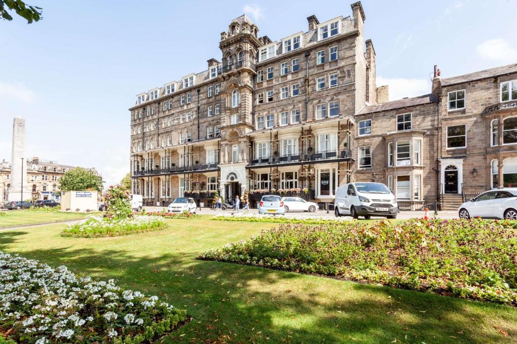 un gran edificio con coches estacionados frente a él en The Yorkshire Hotel en Harrogate