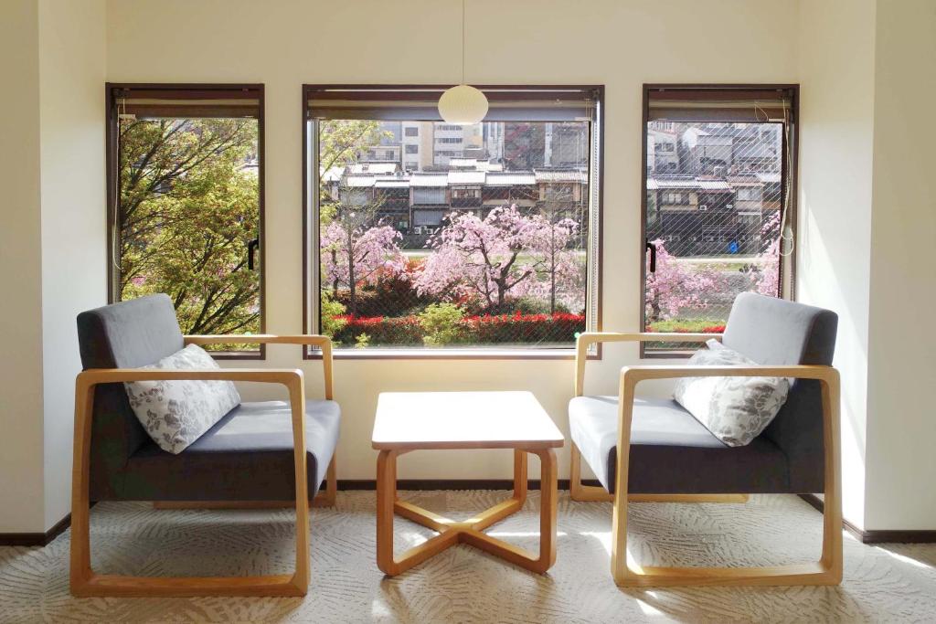 two chairs and a table in a room with windows at RESI STAY Gion in Kyoto