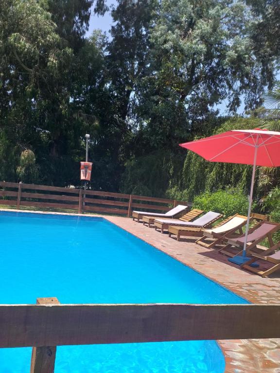 a swimming pool with a red umbrella and lounge chairs at Los Arrayanes in Tandil