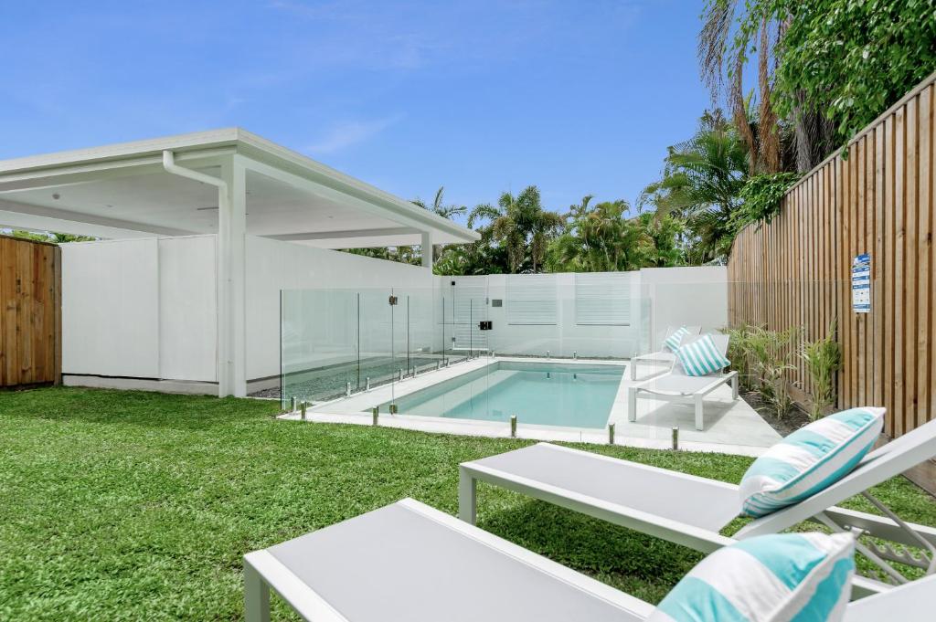 une arrière-cour avec une piscine et des chaises dans l'établissement WhiteSands, à Port Douglas