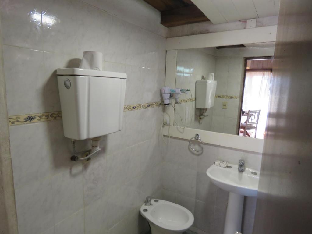 W łazience znajduje się umywalka, toaleta i lustro. w obiekcie La Ruca w mieście Punta del Diablo