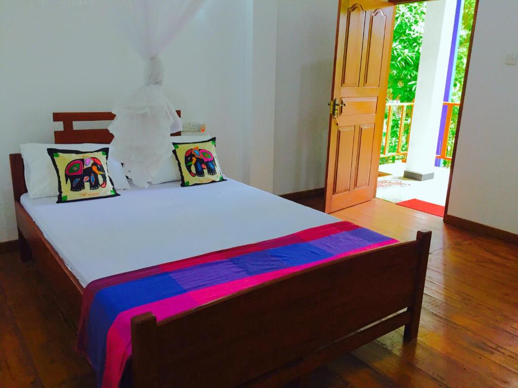 Cama en habitación con suelo de madera en Sigiri Rainbow Lodge, en Sigiriya