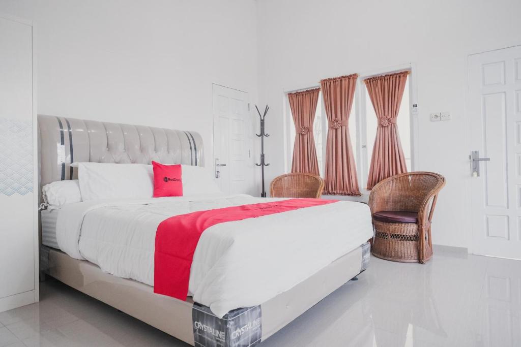 a white bedroom with a large bed with red accents at RedDoorz Syariah near Arafah Hospital Jambi in Jambi