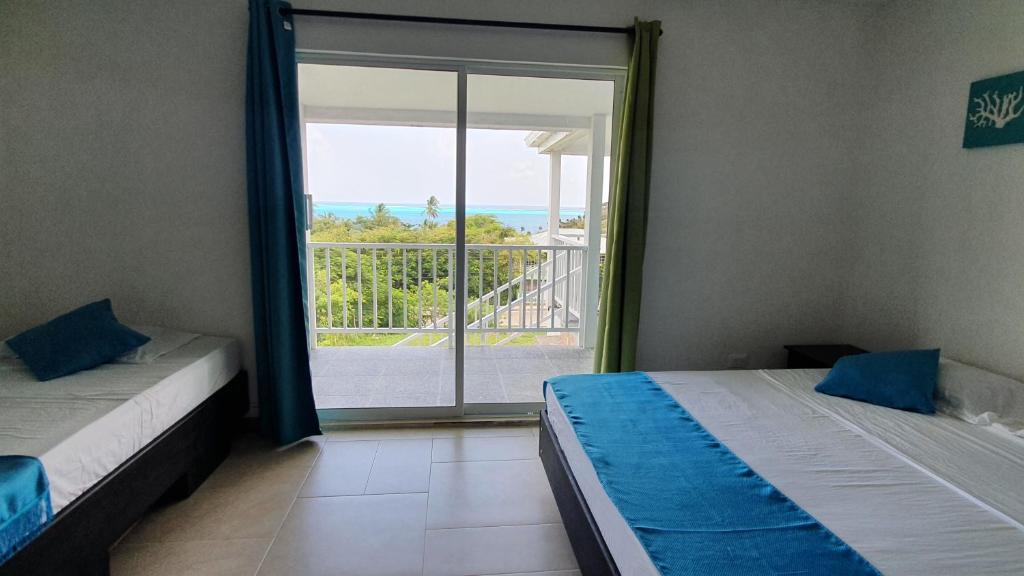 two beds in a room with a view of a balcony at Red Snapper Guest House in Providencia