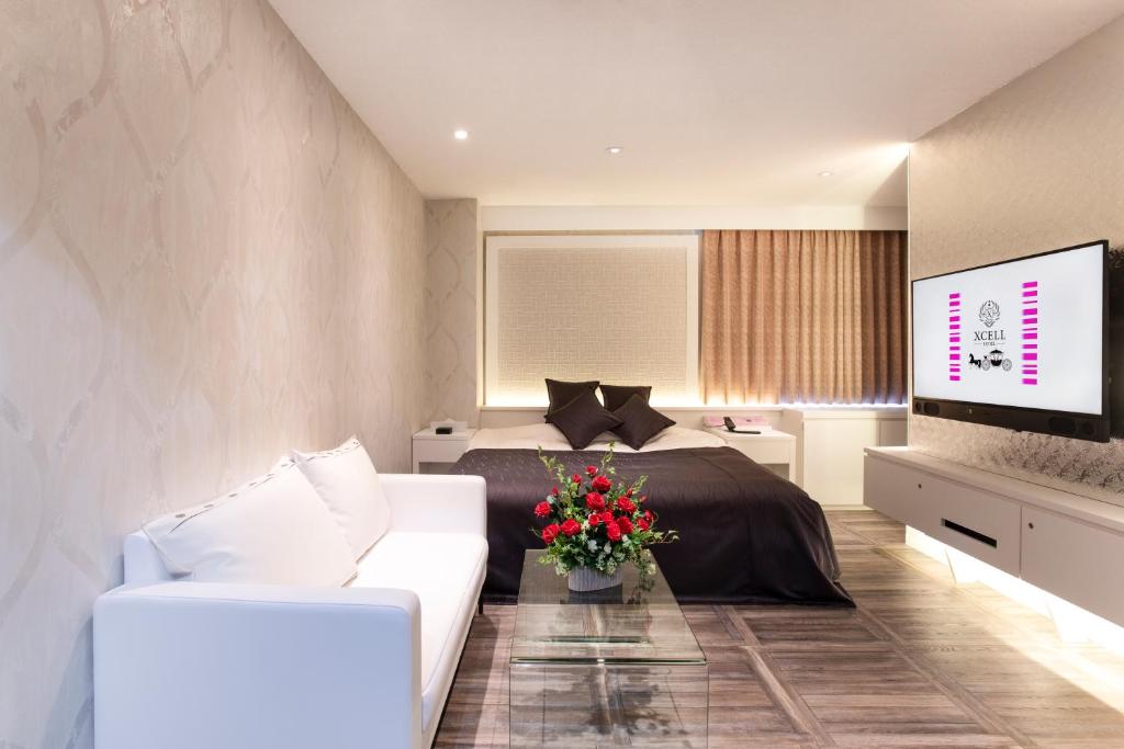 um quarto com uma cama, um sofá e uma televisão em HOTEL xcell em Fukuyama