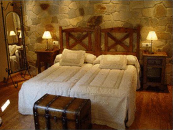 um quarto com uma grande cama branca e uma mala em Centro de Turismo Rural El Recreo em San Martín de Castañeda