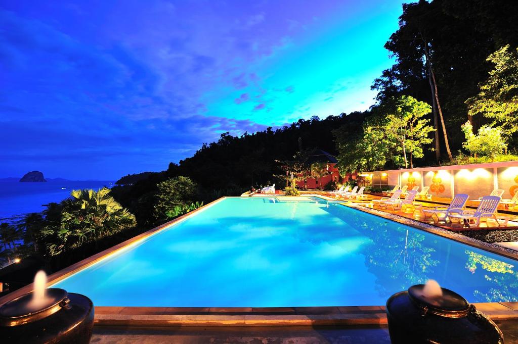 een zwembad met uitzicht op de oceaan in de nacht bij Koh Ngai Cliff Beach Resort in Ko Ngai