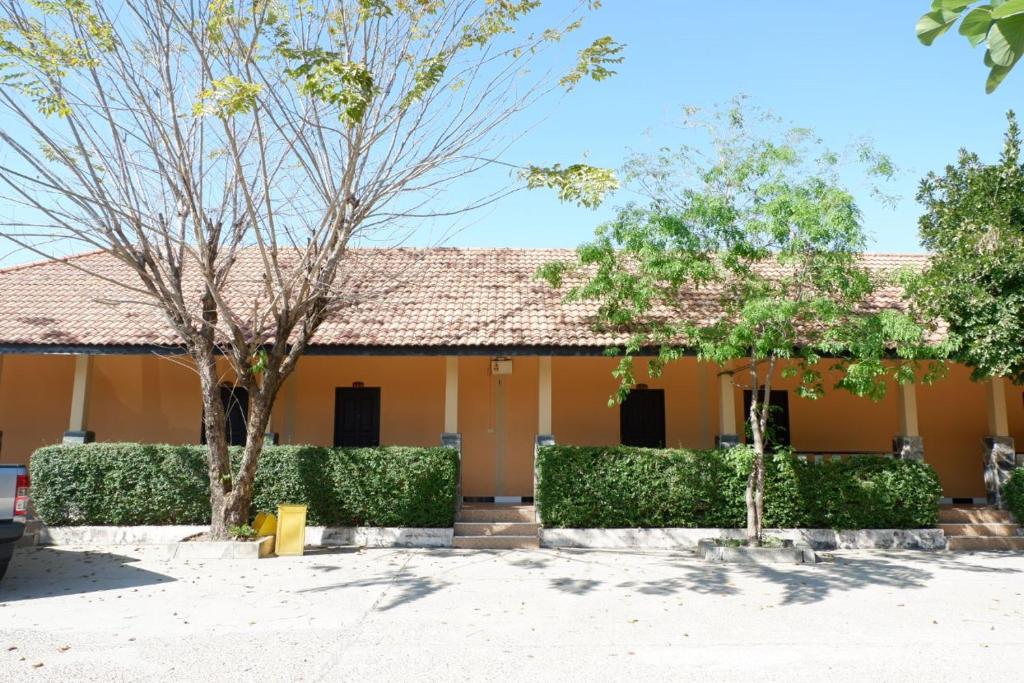 un edificio giallo con alberi di fronte di กิจตรงวิลล์ รีสอร์ท Kittrongvill a Ubon Ratchathani