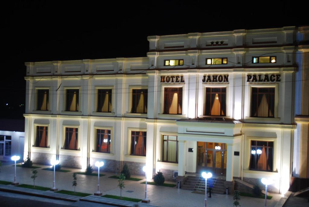 a large white building at night with lights at Jahon Palace in Samarkand