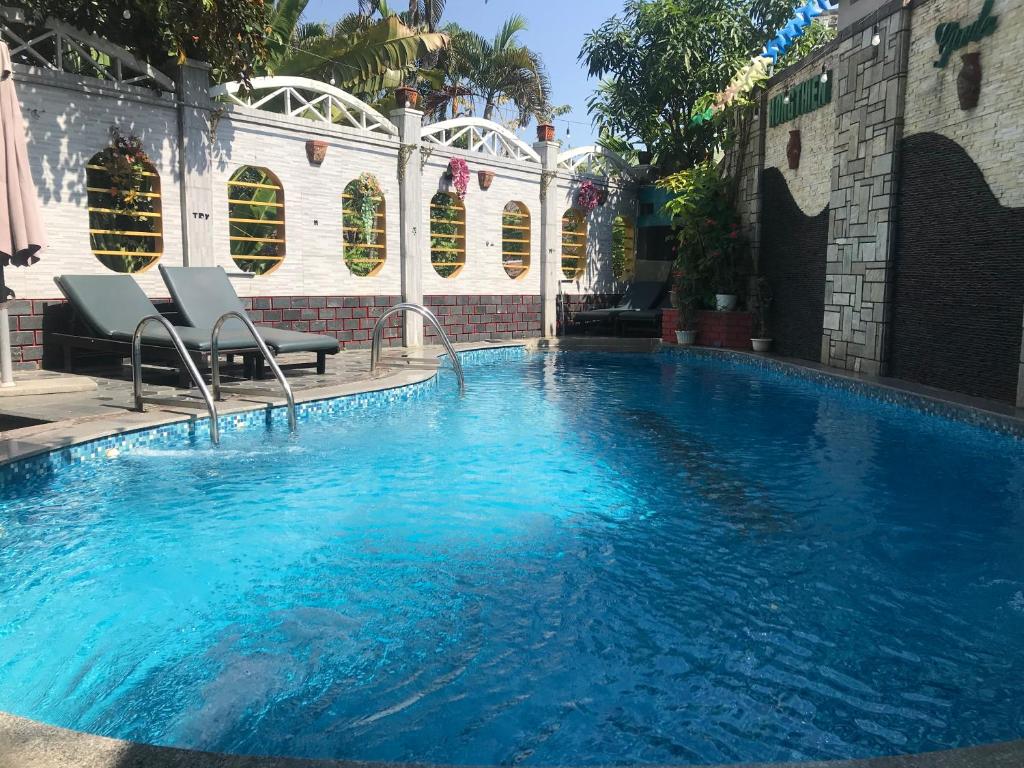 a large swimming pool with two chairs in front of a building at Hong Thien 1 Hotel in Hue