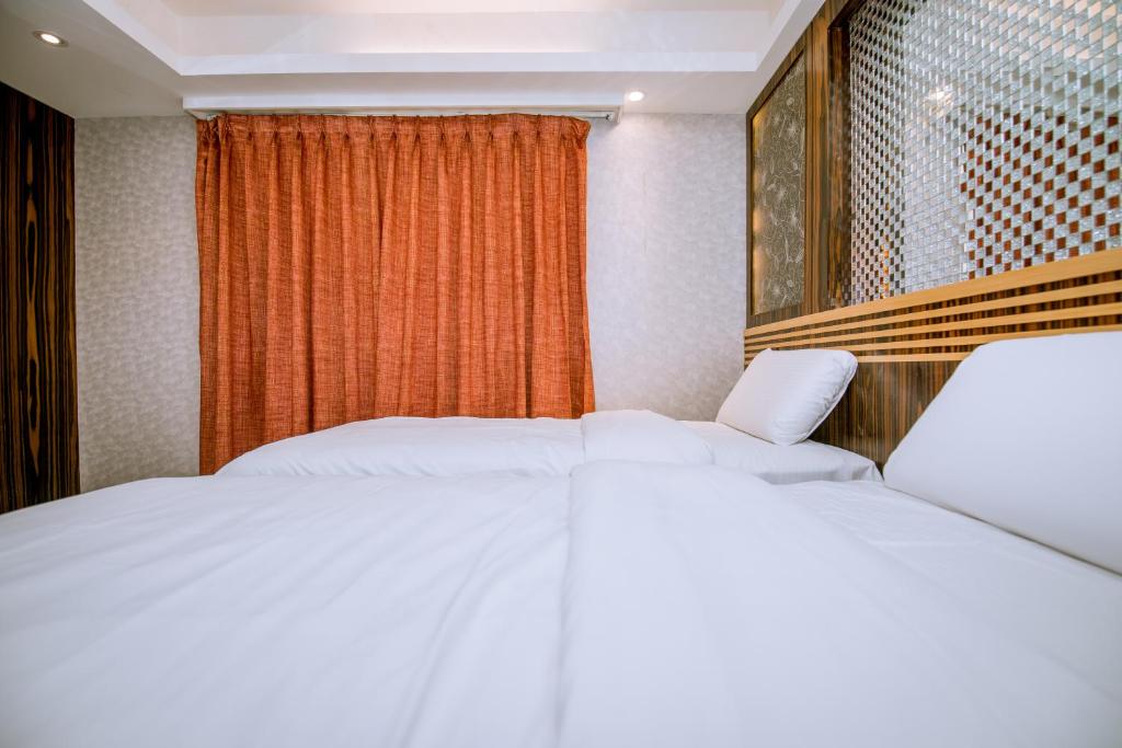 two white beds in a room with a window at Guide Hotel Taipei Xinyi in Taipei
