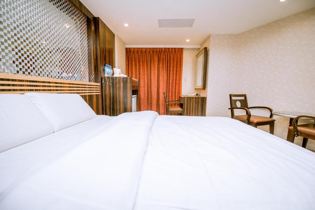 a large white bed in a room with chairs at Guide Hotel Taipei Xinyi in Taipei