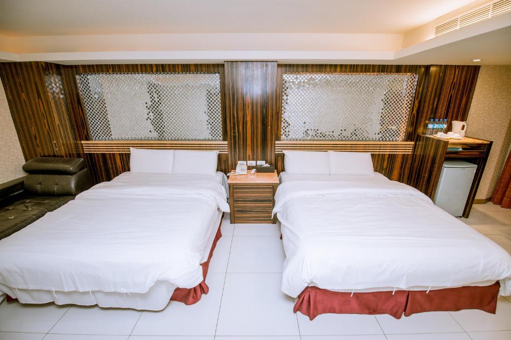 two beds in a hotel room with white sheets at Guide Hotel Taipei Xinyi in Taipei