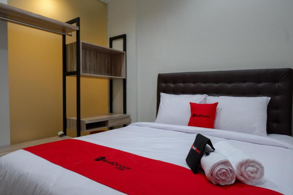 a bed with red and white sheets and red pillows at RedDoorz @ Jalan Kartini Semarang in Semarang