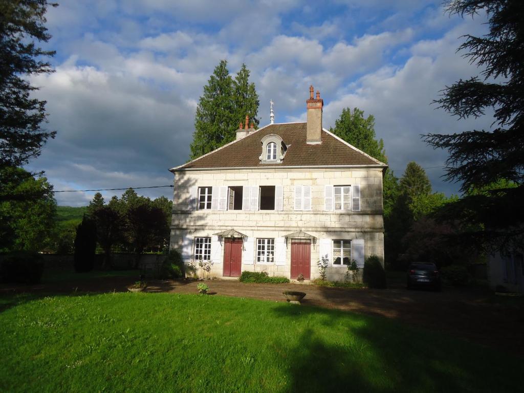 una gran casa blanca con puertas rojas en un patio en Maison de caractere, en La Chapelle-sur-Furieuse
