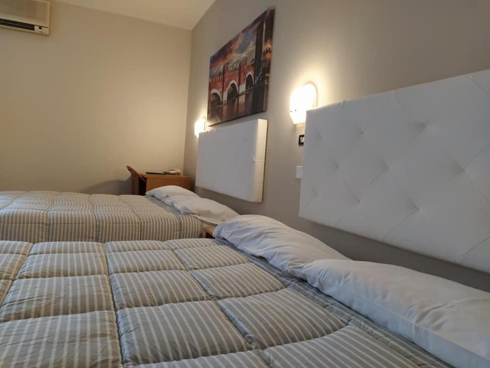 two beds in a hotel room with avertisement at Andreoli & Miglioranzi in San Giovanni Lupatoto