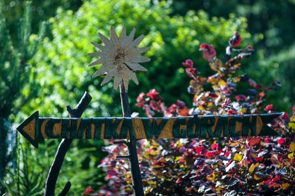 a sign with a flower on it in front of a bush at Chatka w gorach in Lewin Kłodzki