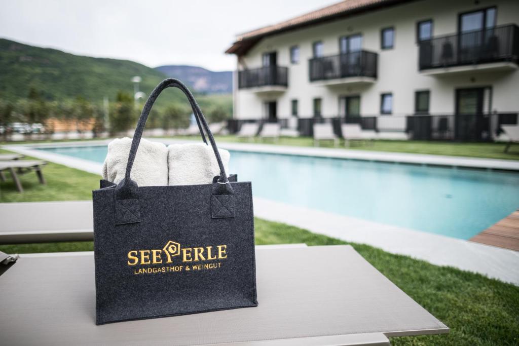 een boodschappentas op een tafel voor een zwembad bij Hotel Landgasthof Weingut Seeperle in Caldaro