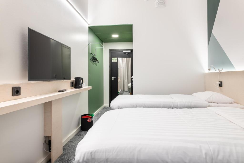 two beds in a room with a flat screen tv at GreenStar Hotel Vaasa in Vaasa