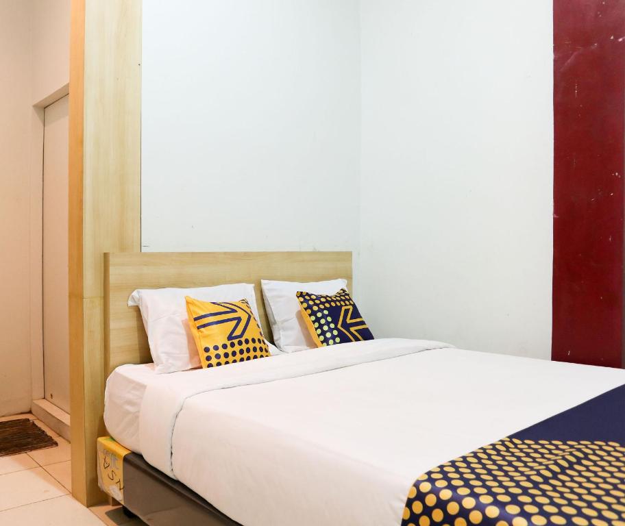パダンにあるSPOT ON 2182 Al-ghani 2 Syariahのベッドルーム1室(黄色と黒の枕付きのベッド1台付)