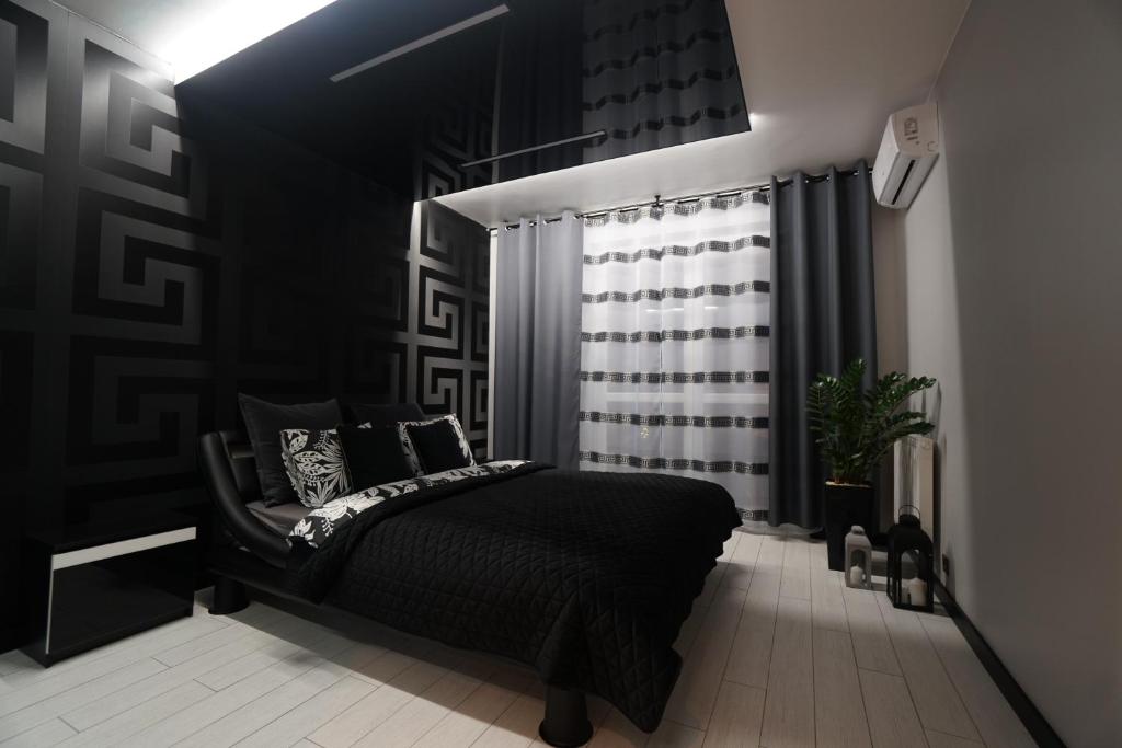 1 dormitorio con cama negra y ventana en Apartament Lema Versace, en Cracovia