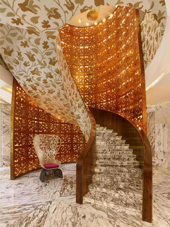 a spiral staircase in a hotel room with a gold wall at The Reverie Saigon in Ho Chi Minh City
