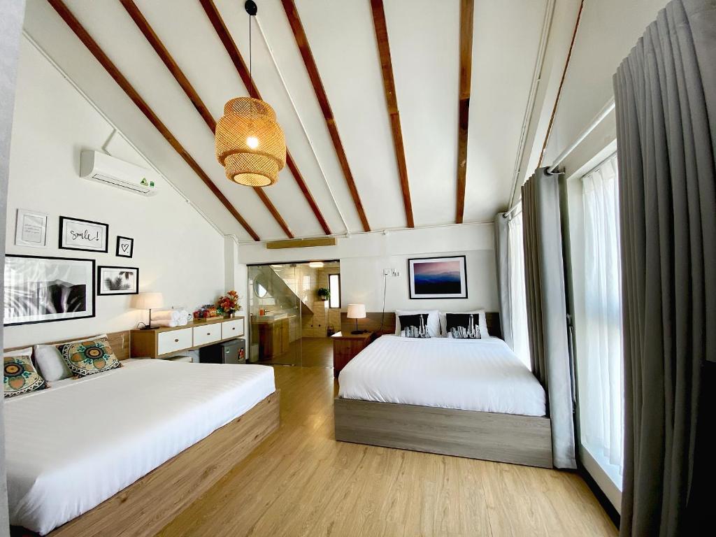a bedroom with two beds and a ceiling with beams at Daisy House in Tuy Hoa