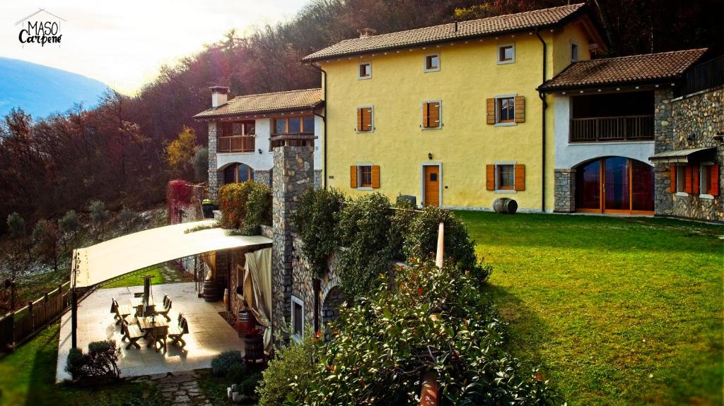 a large yellow house with a table and chairs in a yard at Agritur Maso Carpenè in Rovereto