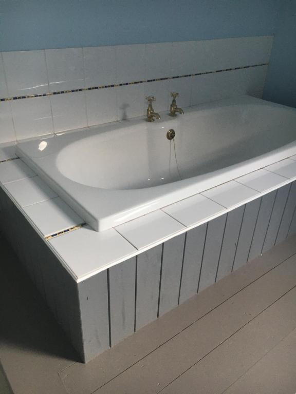 a white bath tub with two faucets in a bathroom at The Carrick in Portrush