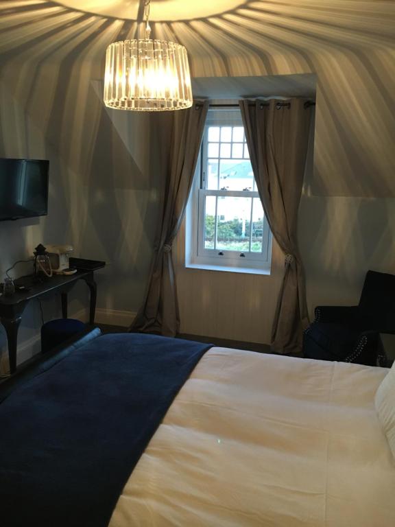 a bedroom with a bed and a window and a chandelier at The Carrick in Portrush
