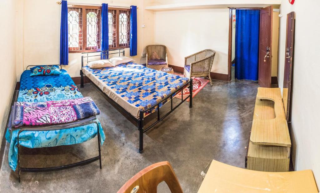 a room with two beds and chairs in it at Blissful Eyrie in Guwahati