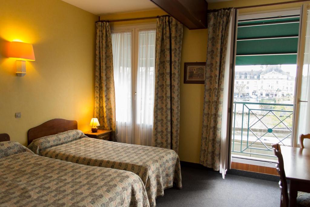 a hotel room with two beds and a large window at Hôtel de Flandre in Compiègne
